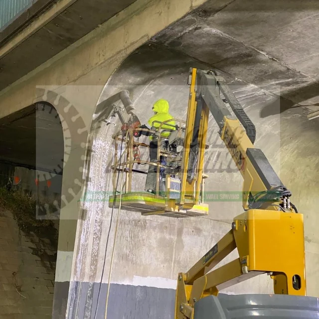 Operator on an elevated work platform beneath a concrete structure