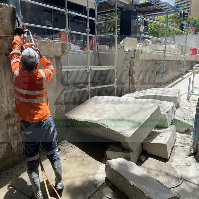 Worker beside cut concrete sections and lifting equipment